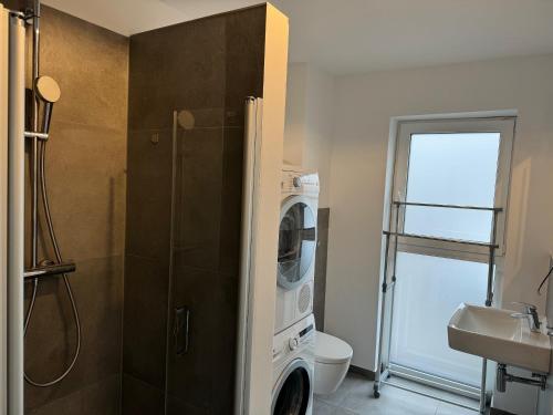 uma casa de banho com uma máquina de lavar e secar roupa ao lado de um lavatório em OTTO Apartments em Hamburgo