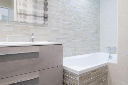 une salle de bain avec un lavabo et une baignoire dans l'établissement Grande maison avec piscine, proche océan, Les Sables, 6 personnes, à Les Sables-dʼOlonne