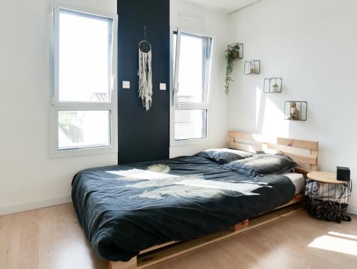 une chambre avec un grand lit et deux fenêtres dans l'établissement Grande maison avec piscine, proche océan, Les Sables, 6 personnes, à Les Sables-dʼOlonne