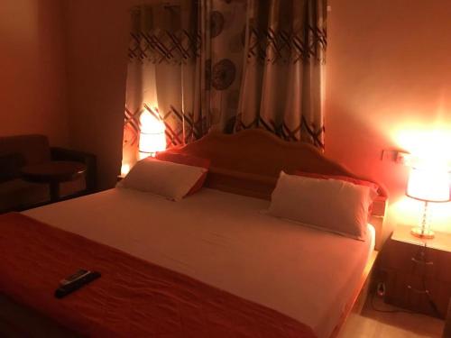 ein Schlafzimmer mit einem großen weißen Bett mit einer Lampe in der Unterkunft JEMP INN HOTEL in Asamankese