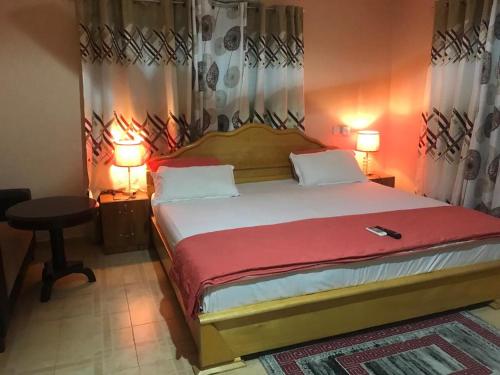a bedroom with a large bed with two lamps and a table at JEMP INN HOTEL in Asamankese