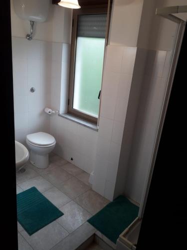 a bathroom with a toilet and a window and green mats at Tramonto sul Tirreno in Acquappesa