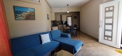 a living room with a blue couch and a kitchen at Smailis apartment 1 in Koróni