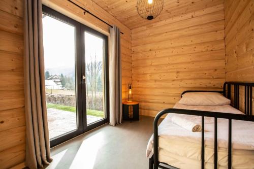 a bedroom with a bed and a large window at Gorczański dom z bali w górach in Poręba Wielka