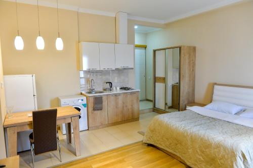 a bedroom with a bed and a desk and a kitchen at Cozy Apartment In Old Town Kutaisi in Kutaisi