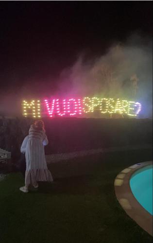 a woman standing in front of a welcome sign at night at Il Rustico in Pozzillo