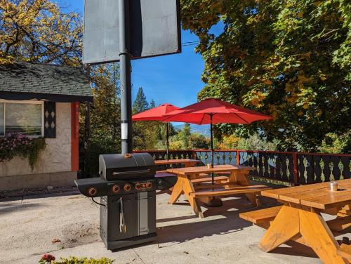 a group of picnic tables with a grill and red umbrella at Alpine Inn & Suites in Nelson
