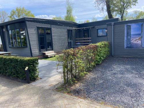 a gray house with a bench in front of it at Luxe Chalet 146 in Putten