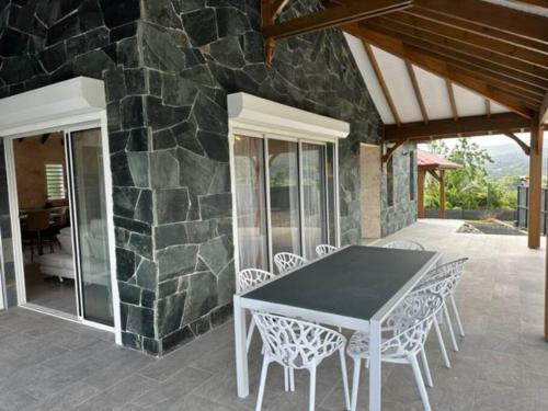 un tavolo e delle sedie su un patio con un muro di pietra di Villa Choisy a Sainte-Rose