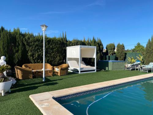 um quintal com uma piscina com cadeiras e uma casa em Villa Española em Elche