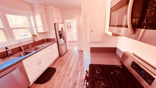 uma cozinha com armários brancos, um lavatório e um fogão em Los Angeles Dream Cottage em Los Angeles