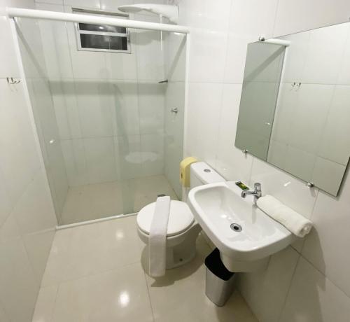 a white bathroom with a toilet and a sink at Itaipu Hotel Foz do Iguaçu in Foz do Iguaçu