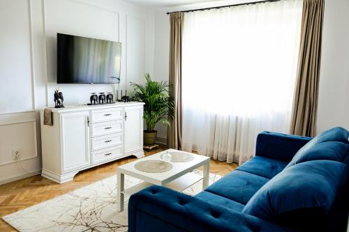een woonkamer met een blauwe bank en een tv bij Clover Apartament in Cluj-Napoca