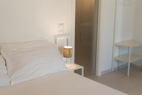 a bed with white sheets and a lamp on a table at Endea Suite Rooms & Lounge SPA in Matera