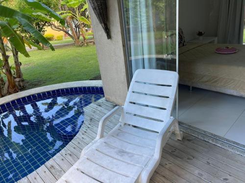 a white chair sitting next to a swimming pool at Apartamento Villas do Pratagy in Maceió