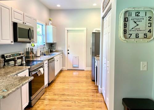 a kitchen with white cabinets and a clock on the wall at Tampa Heights Bungalow in Tampa