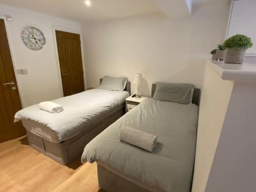 Zimmer mit 2 Betten und einer Uhr an der Wand in der Unterkunft LT Apartments 54 - Twin Bed Apartment in Leicester