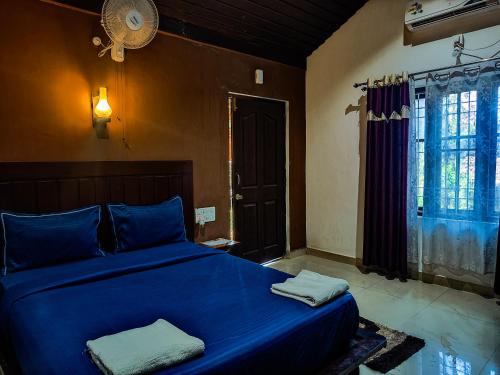 a bedroom with a blue bed and a window at The Twin Cottages in Madikeri