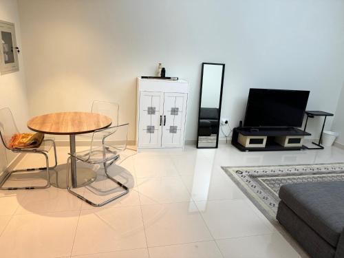 a living room with a table and a television at 1 BHK in Al Khan Sharjah in Sharjah