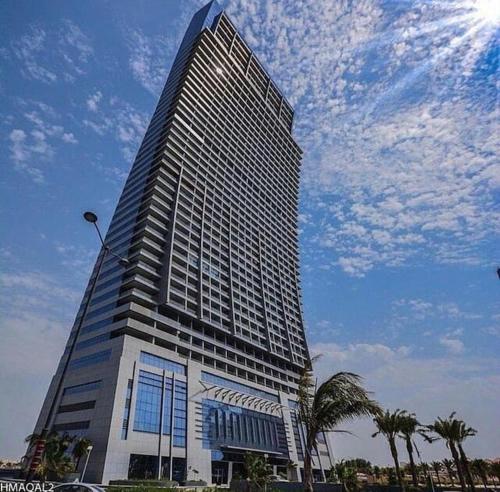 a tall building with palm trees in front of it at Damac Tower Jeddah apartment in Jeddah