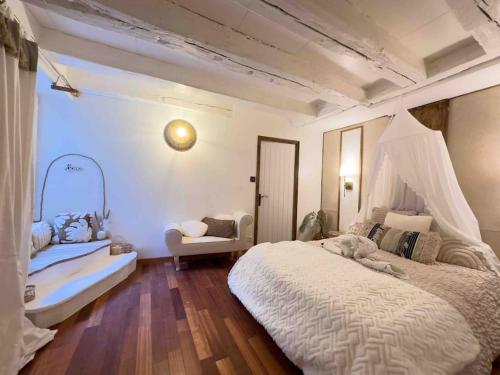 une chambre avec un grand lit blanc et une chaise dans l'établissement LES SEYCHELLES, T2, Hyper Centre, Cours intérieure, à Mâcon