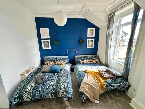 two beds in a room with blue walls at Cosy stylish Dumbarton flat in Dumbarton