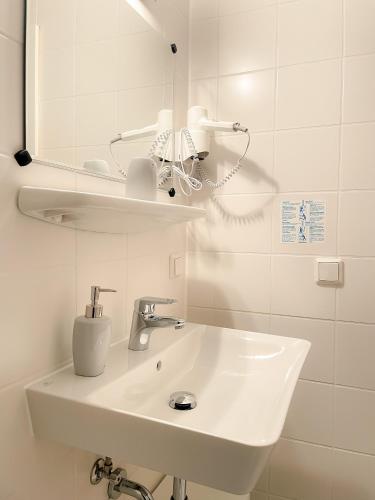 a white bathroom with a sink and a mirror at Altstadt-Hotel in Freiberg