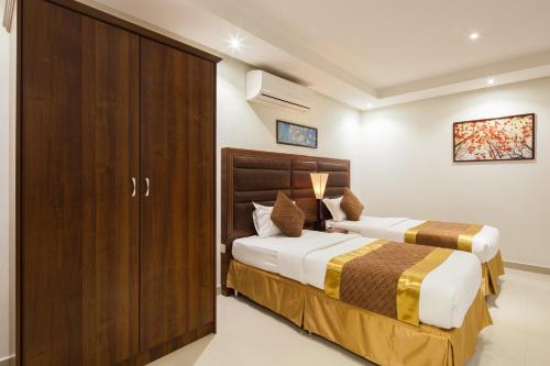 a bedroom with two beds and a cabinet at Burj Alhayah Alfalah in Riyadh
