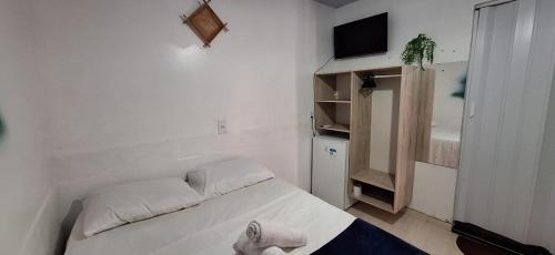 a small white bedroom with a bed and a tv at Pousada Angatu alter in Alter do Chao