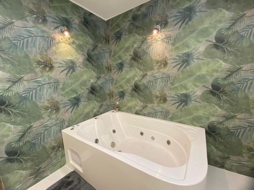 a bath tub in a bathroom with a tropical wallpaper at Hermosa suite 2 cerca de todo in Guayaquil