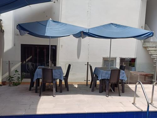 two blue umbrellas over a table and chairs next to a pool at HBCF Hotel Boutique Casa Farallones de Santiago de Cali in Cali