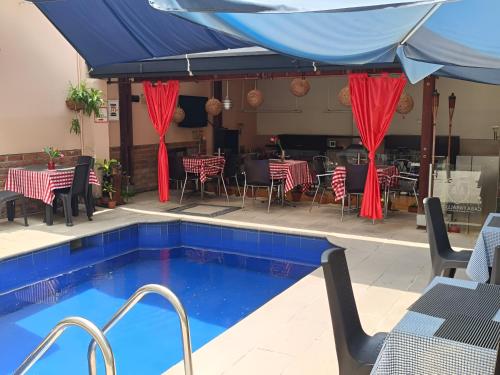 a swimming pool with a blue umbrella and tables and chairs at HBCF Hotel Boutique Casa Farallones de Santiago de Cali in Cali