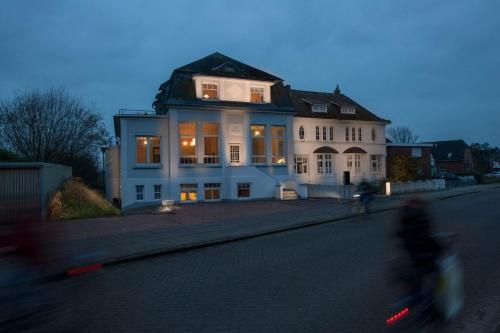 a person riding a bike in front of a house at FeWo Konstanze in Borkum