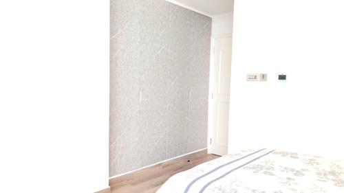 biały pokój z łóżkiem i ścianą w obiekcie Ms. Zhang's Flat 303 w Abu Zabi