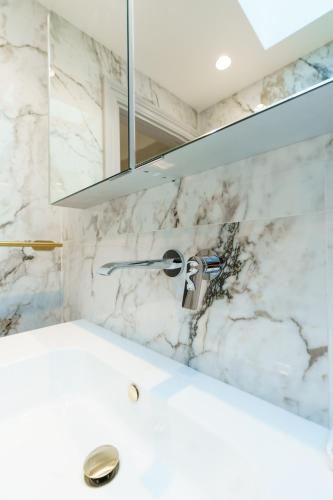 a white bathroom with a sink and a mirror at Holland Park Residence in London