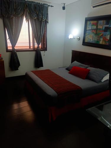 a bedroom with a bed with a red blanket and a window at HBCF Hotel Boutique Casa Farallones de Santiago de Cali in Cali