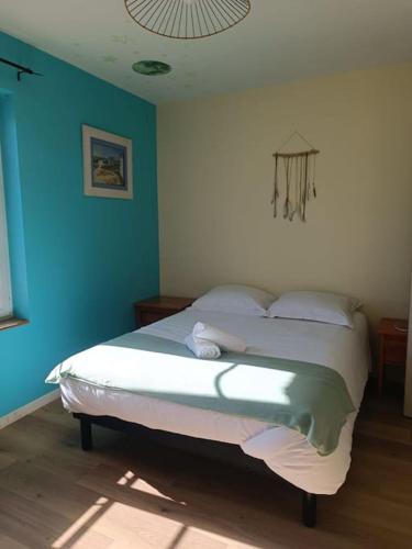 une chambre avec un lit avec un mur bleu dans l'établissement Maison au cœur du village avec parking, à Étretat