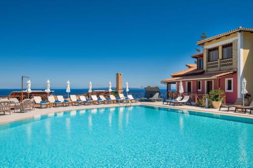 a swimming pool with chairs and the ocean in the background at Sea View Village in Vasilikos