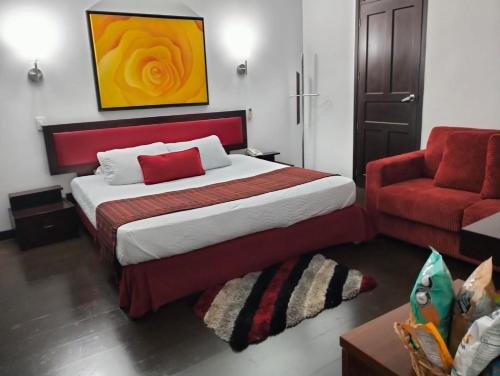 a bedroom with a bed and a red chair at HBCF Hotel Boutique Casa Farallones de Santiago de Cali in Cali
