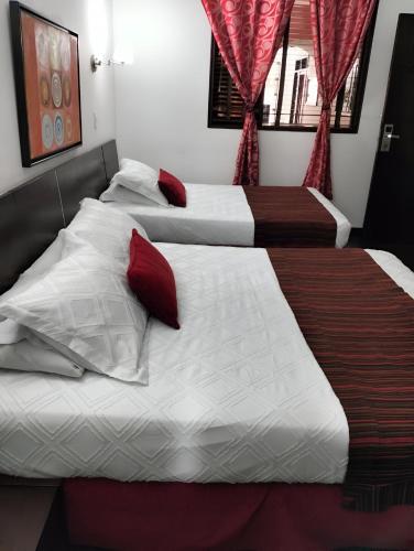 two beds in a hotel room with red curtains at HBCF Hotel Boutique Casa Farallones de Santiago de Cali in Cali