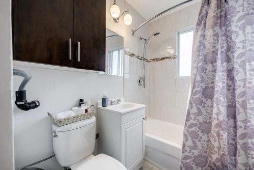 a bathroom with a toilet and a sink and a tub at Eglinton West Guest Suite in Toronto
