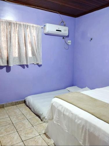 a bedroom with two beds and a window with a fan at 7 camas de casal - Casa próxima ao Bumbódromo in Parintins