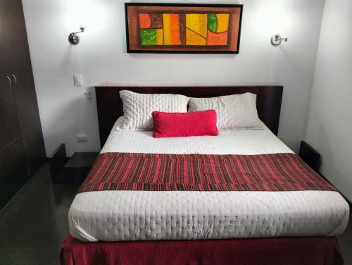 a bedroom with a bed with a red pillow at HBCF Hotel Boutique Casa Farallones de Santiago de Cali in Cali