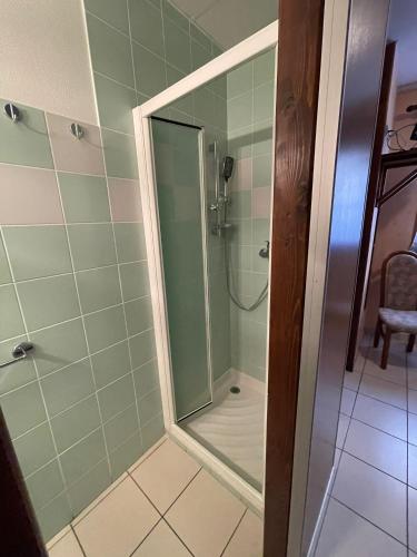 une salle de bain avec une douche avec une porte vitrée dans l'établissement Hôtel Elaïa, à Corps