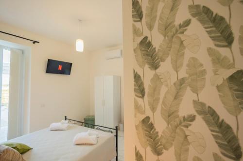 1 dormitorio con un mural de hojas en la pared en Cientopera Suite Rooms, en Pontecagnano Faiano