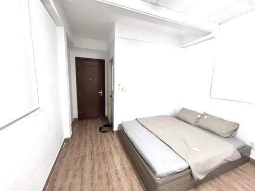 a bed in a white room with a wooden floor at Kevin homestay in Ho Chi Minh City