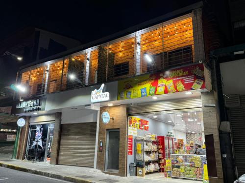 un magasin situé sur le côté d'une rue la nuit dans l'établissement Apartaestudios La capital, à San José
