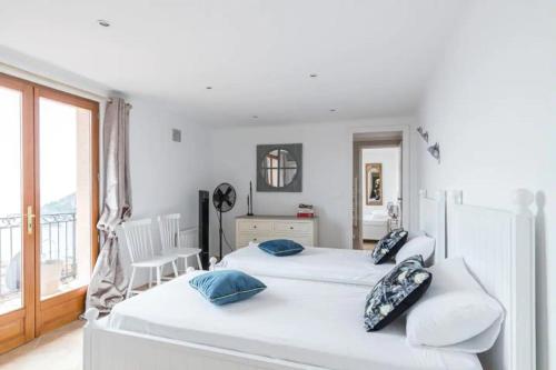 - une chambre blanche avec 2 lits et un balcon dans l'établissement Villa de luxe à Eze, à Èze