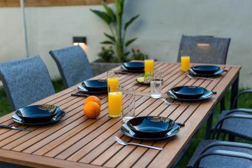 a wooden table with plates and oranges and glasses of orange juice at SeaviewHeaven - Private pool - Overlooking Chania in Chania Town