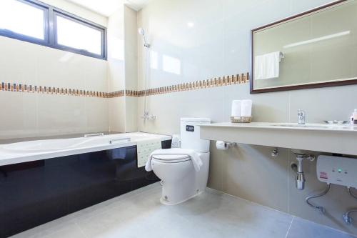 a bathroom with a toilet and a sink and a mirror at The Sita Princess in Buriram